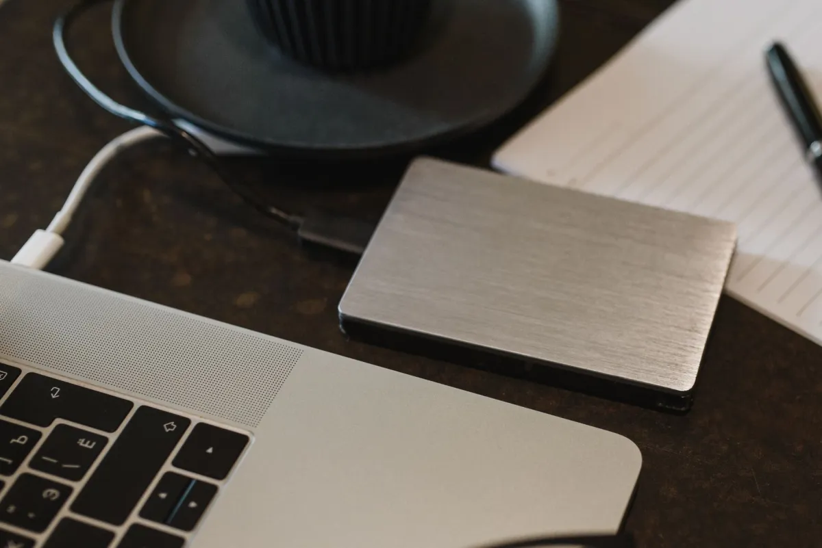 An external drive connected to a laptop by a cable on a desk.