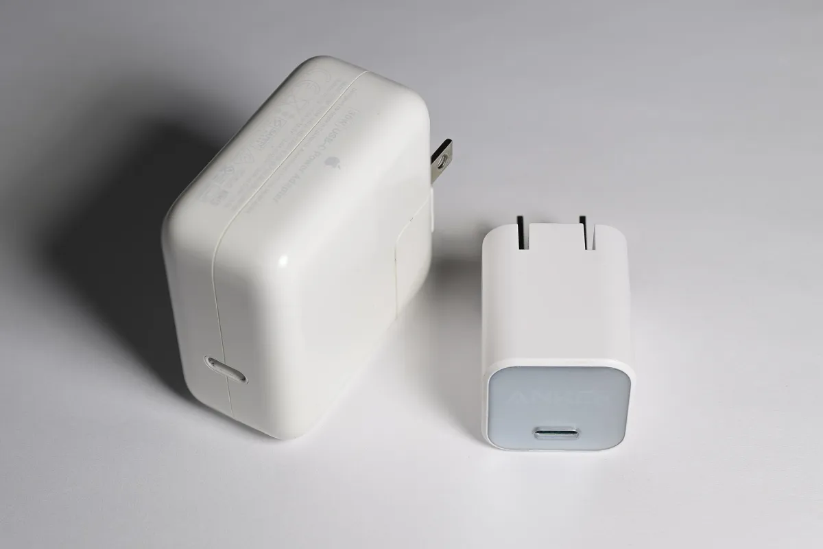Two white USB-C mains chargers of different sizes, with their USB-C sockets and mains pins visible.