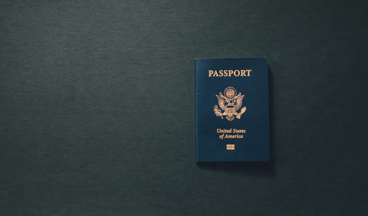 A closed blue United States passport lies on a dark textured surface.
