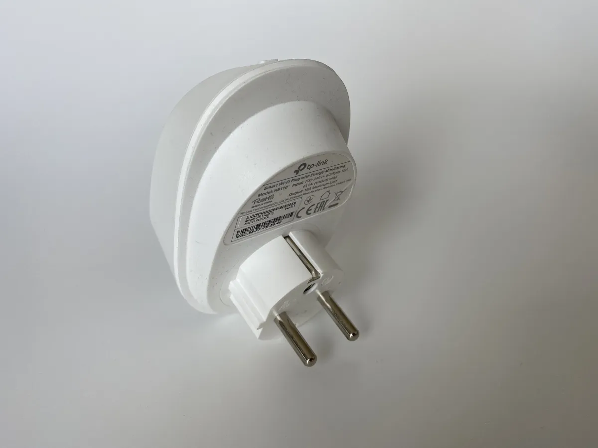 Real white TP-Link HS110 smart Wi-Fi plug viewed from behind, showing its model label and two round mains pins.