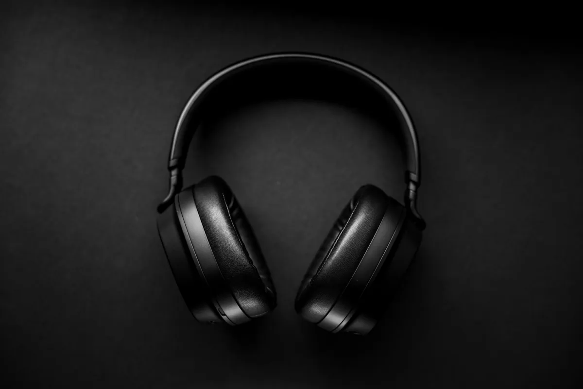 Black over-ear headphones resting on a dark textured surface.