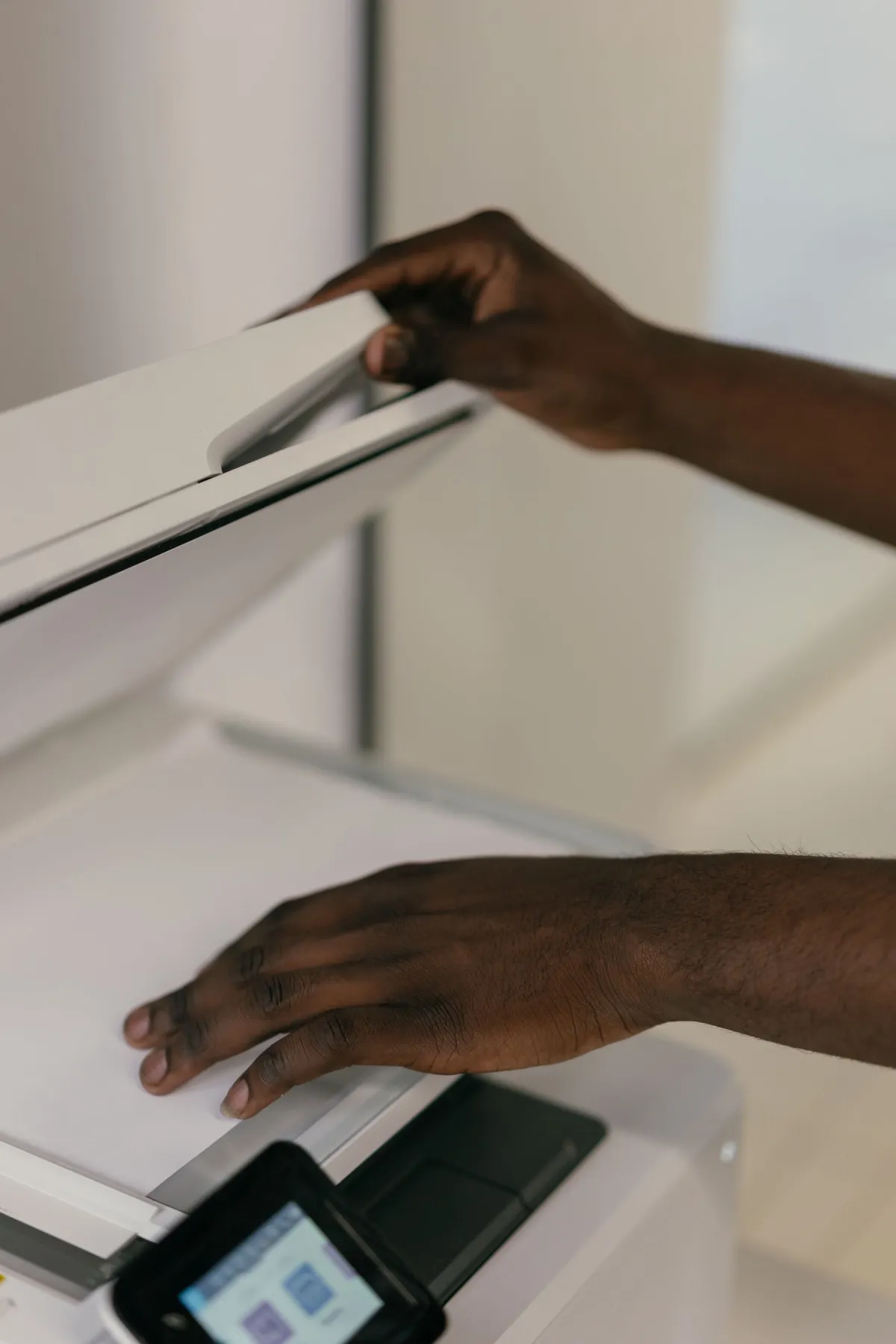 Hands positioning a paper document on an office scanner