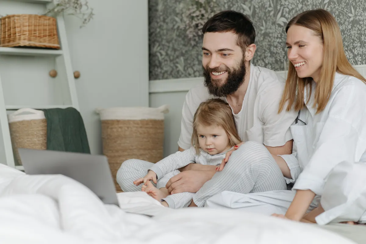Two adults and a child looking at a laptop together at home.