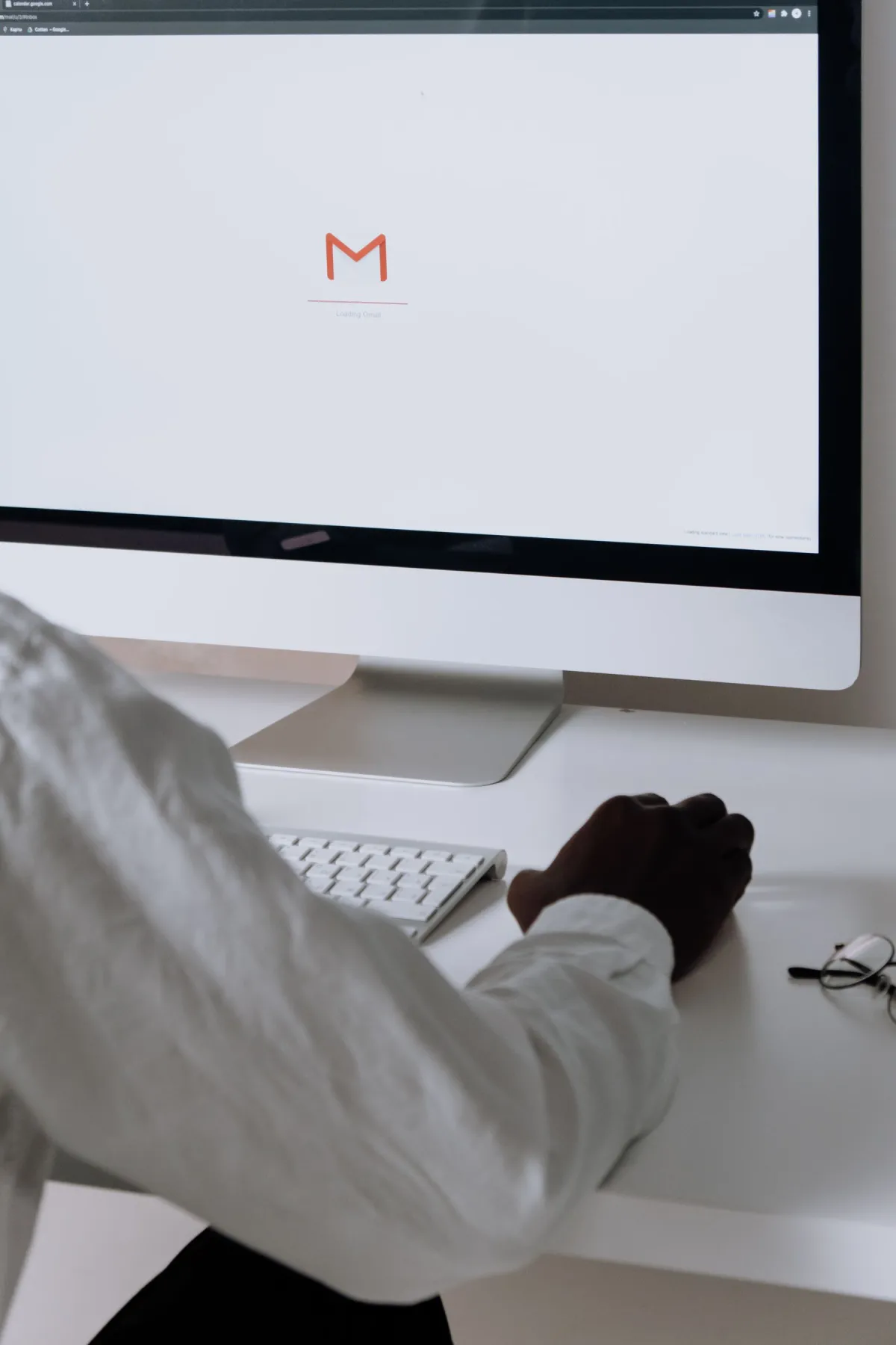 A person seated at a desk checking messages on a desktop computer.