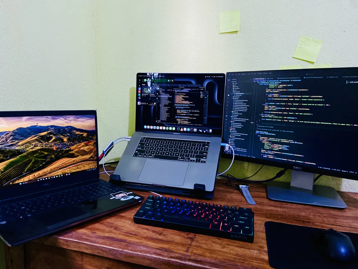 Home office desk with two laptops, an external monitor, keyboard and visible connecting cables.