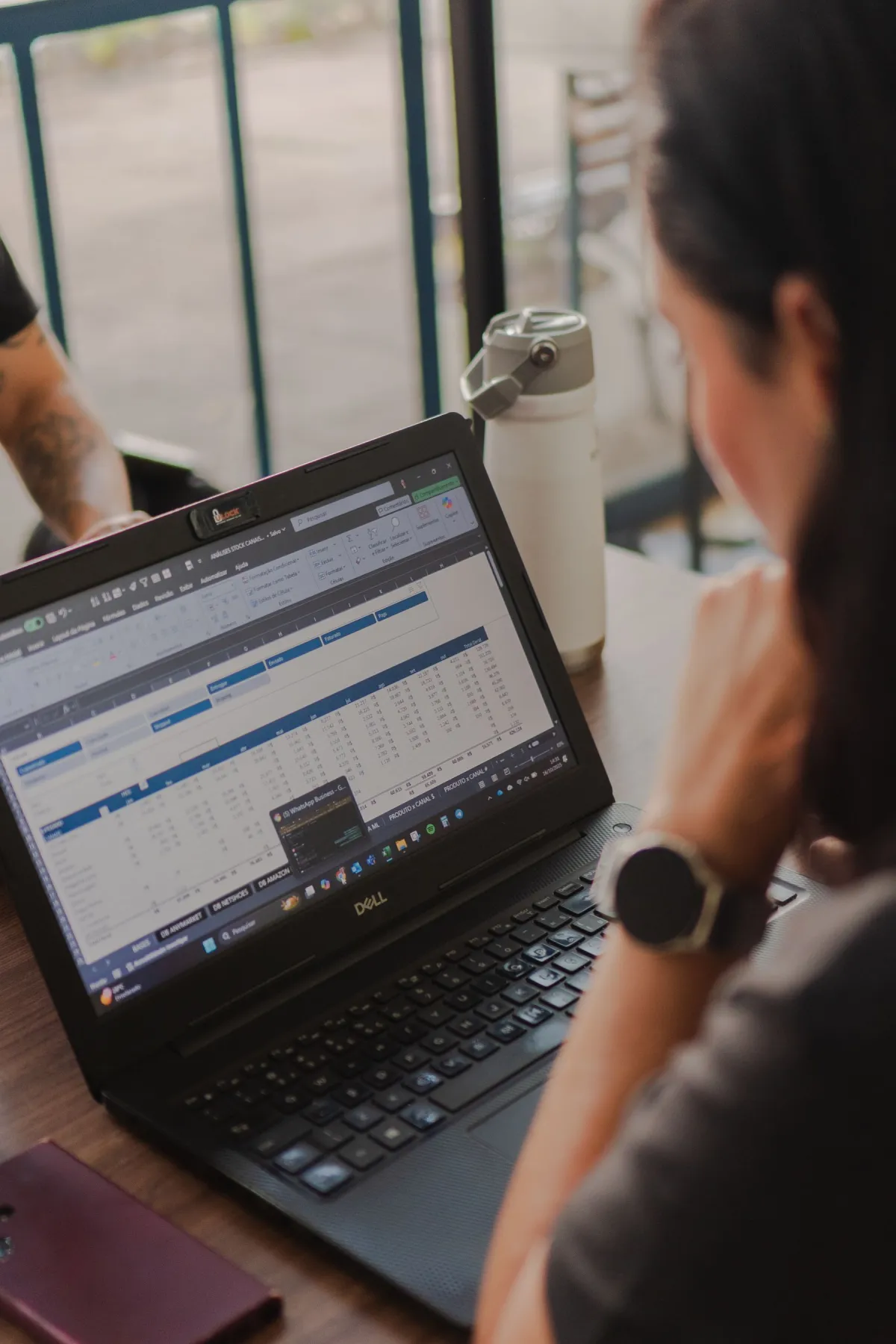 Person reviewing spreadsheet rows on a laptop screen at a table