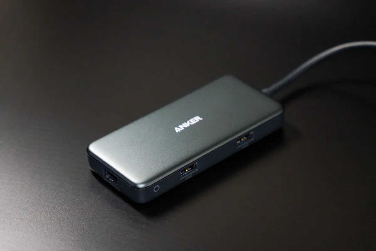 A compact USB-C hub with several ports on a dark desk.
