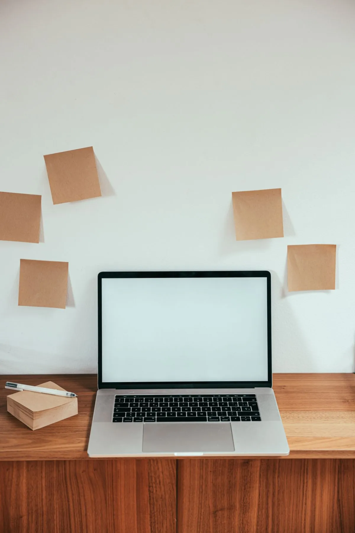 An open laptop with a blank screen and sticky notes on a wooden desk