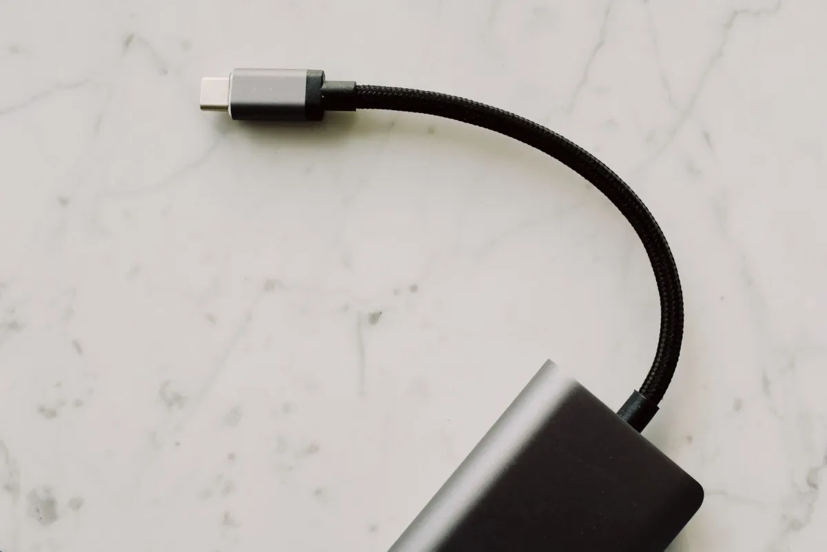 A USB-C connector on a braided hub cable resting on marble