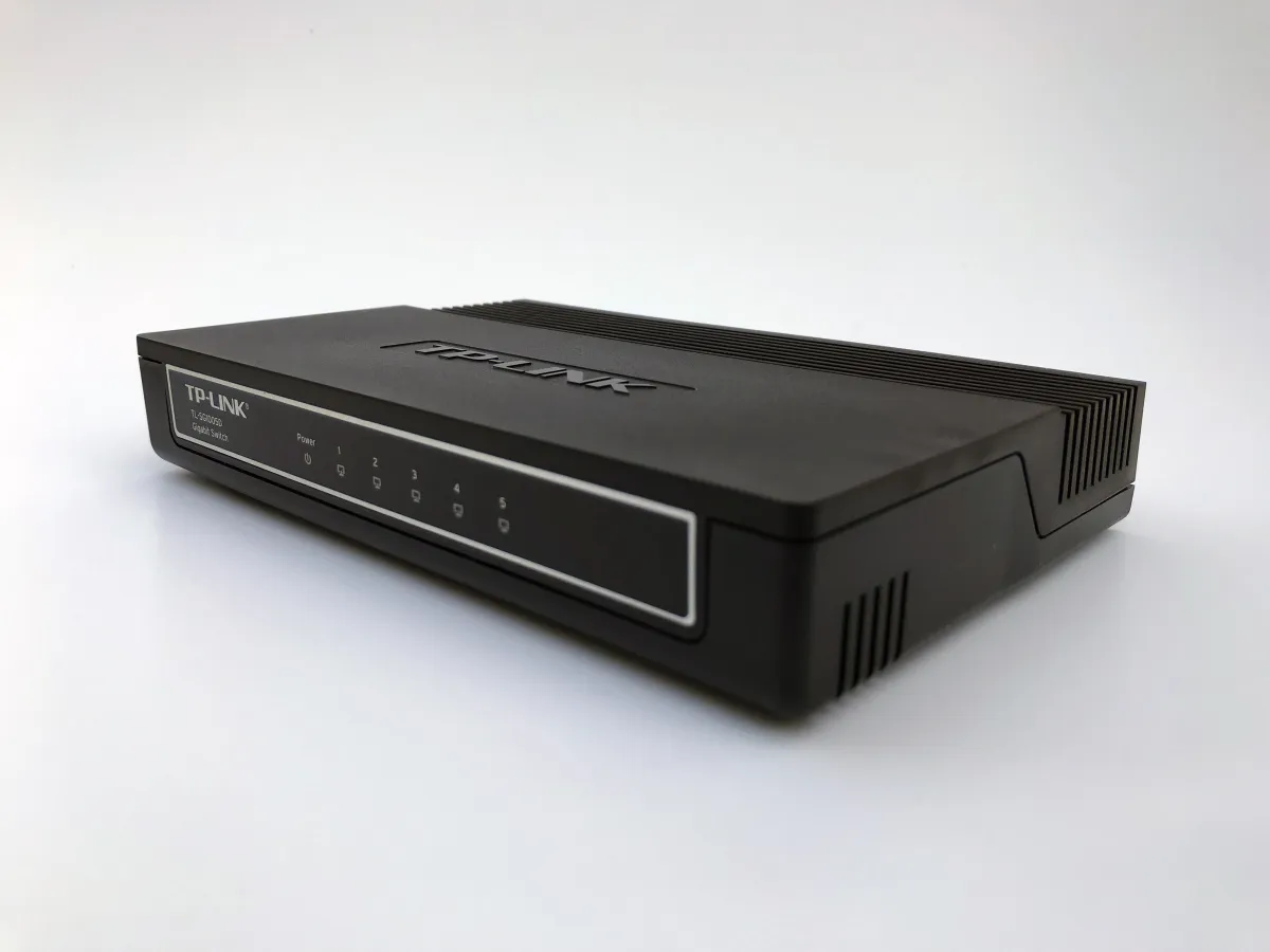 Black TP-Link TL-SG1005D desktop Ethernet switch photographed on a white surface, with five numbered indicator positions on its front.