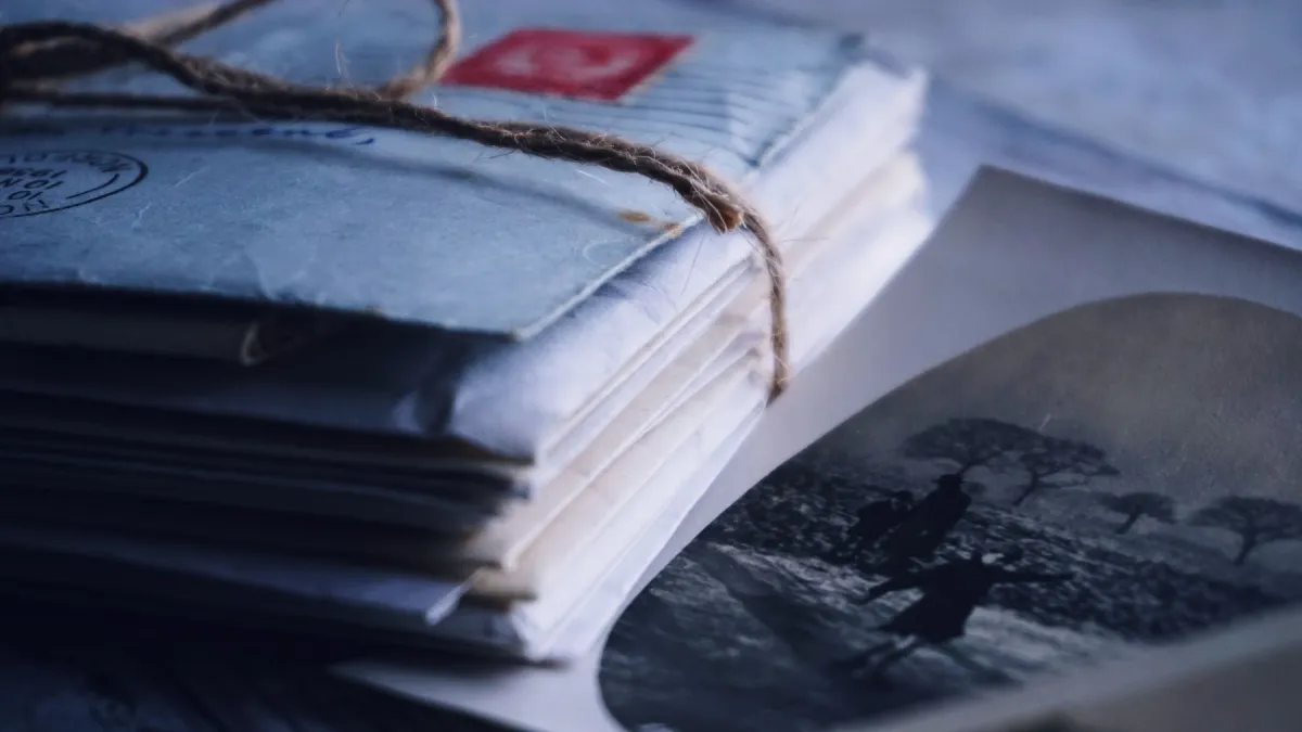 A bundle of vintage envelopes tied with twine beside an old black-and-white photograph.