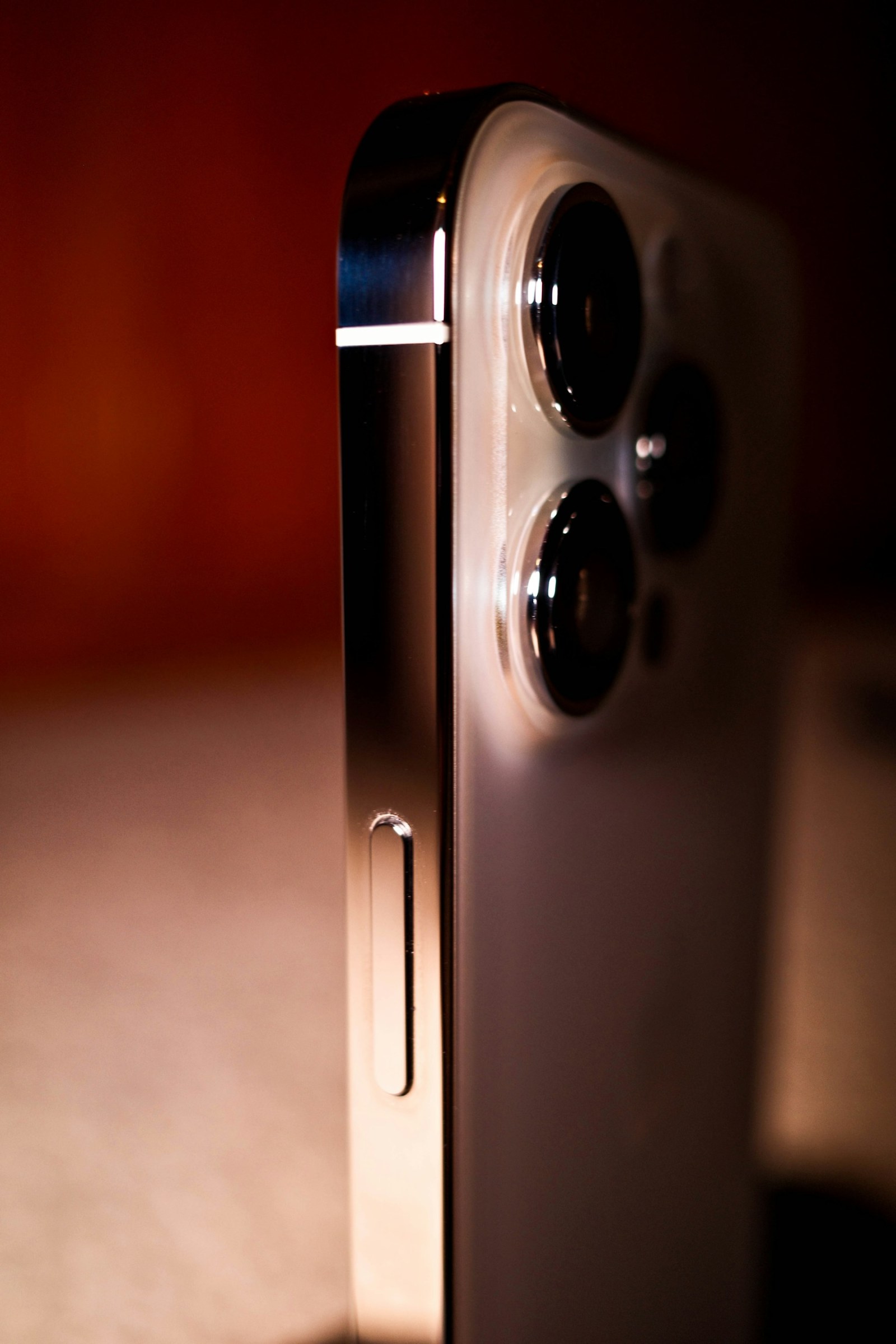 Angled close-up of an iPhone rear camera cluster, raised lens rings and adjacent metal frame.