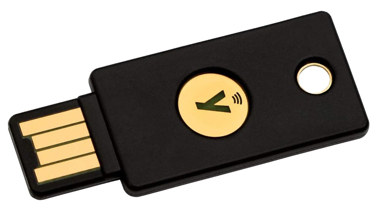 Closeup of a black YubiKey with four exposed USB contact strips at left and a separate round gold touch disc on its body.
